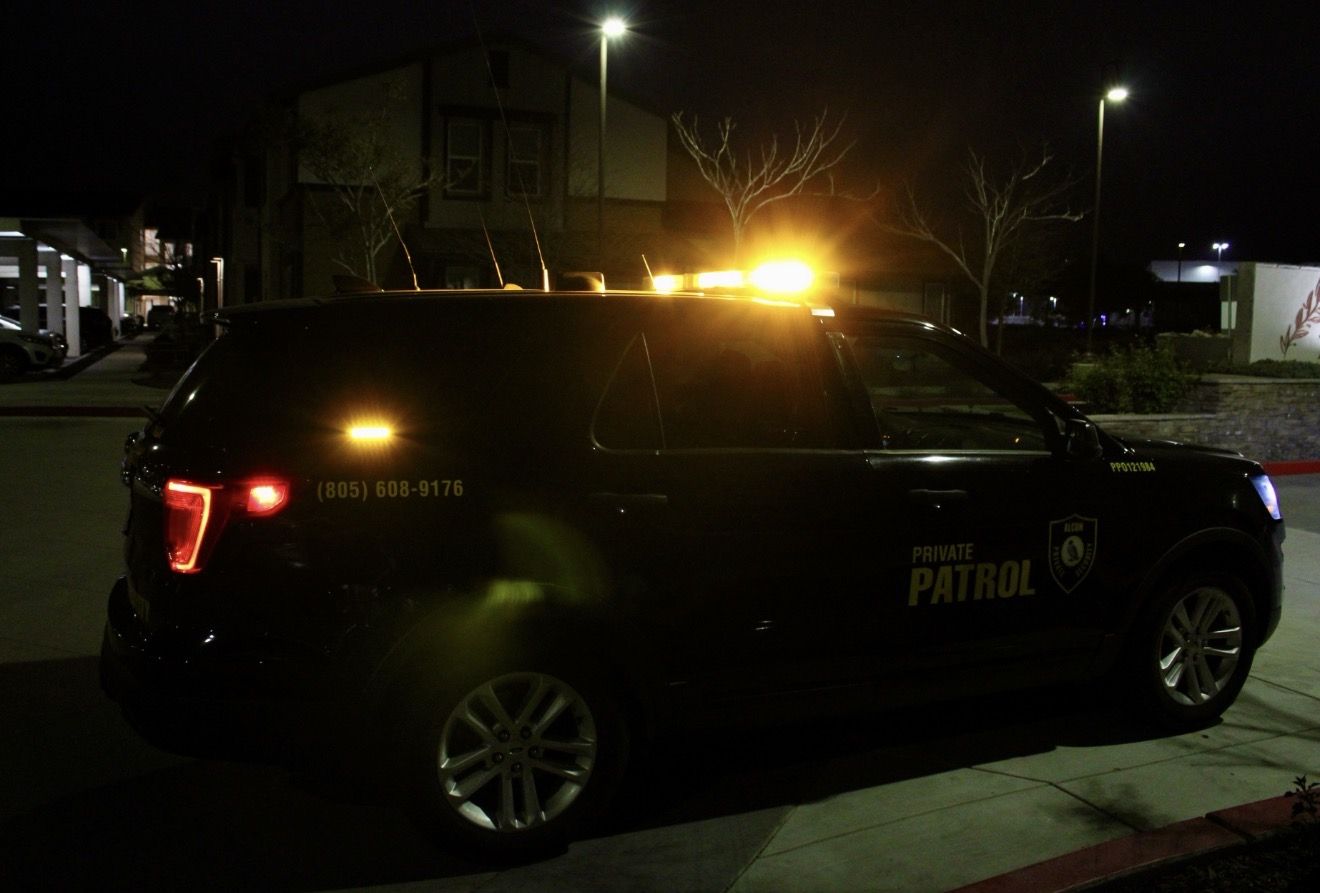 Alcon patrol SUV with amber beacon lit outside a building at night