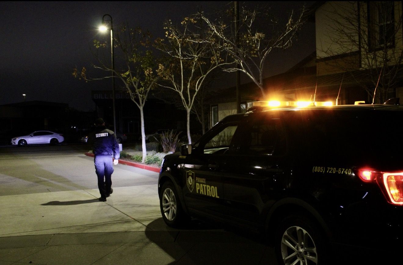 Alcon officer on foot patrol at night with the patrol SUV's amber lights on