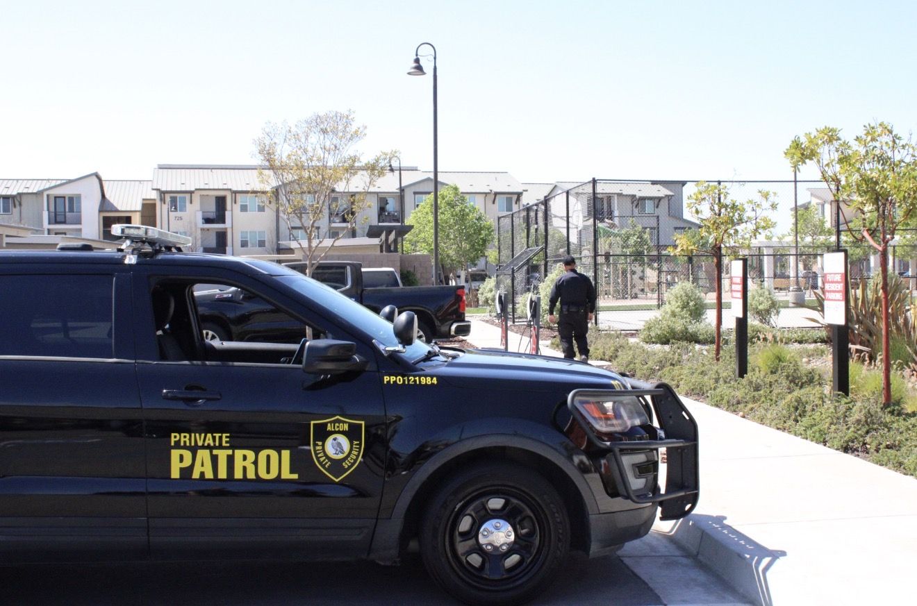 Alcon officer walking a property patrol next to the marked SUV