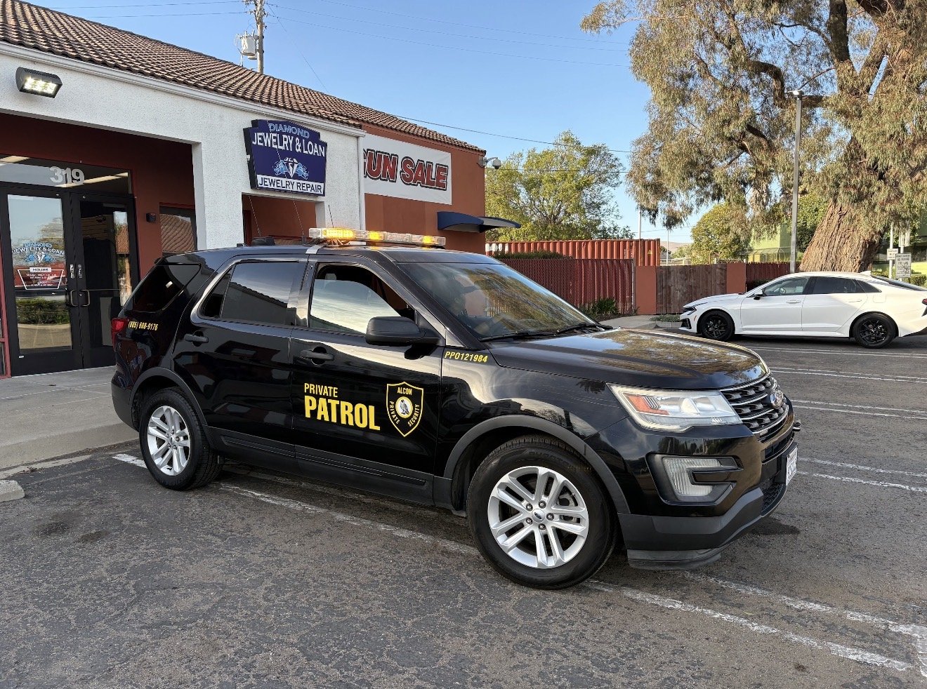 Marked Alcon Private Patrol SUV parked outside a local storefront in daylight